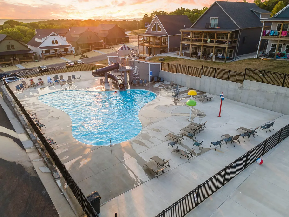 This exterior image displays a vibrant swimming pool with a water slide, colorful water features, and plenty of lounge chairs for relaxing. The setting is lively and cheerful, ideal for group fun and family gatherings.