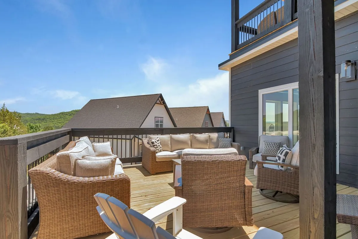 A serene wooden deck with comfortable seating and a scenic view of the surrounding natural environment. The setting exudes tranquility and is ideal for morning coffee or quiet moments spent with a pet, framed by lush greenery and open skies.