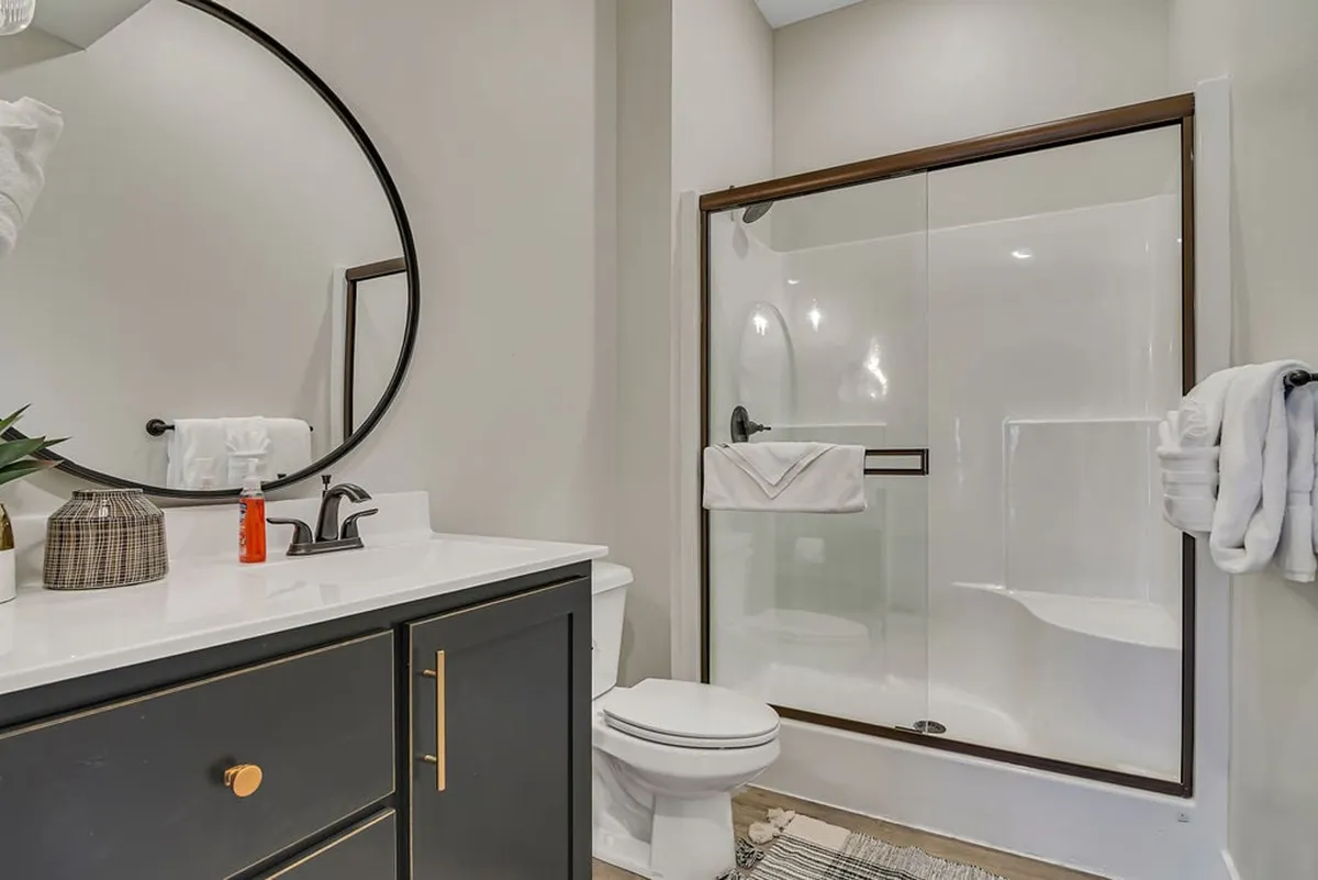 A bright, modern ensuite bathroom with a vanity mirror, glass-enclosed step-in shower, and sink. Clean lines and calming tones create a spa-like environment—perfect for refreshing after a day of adventure.