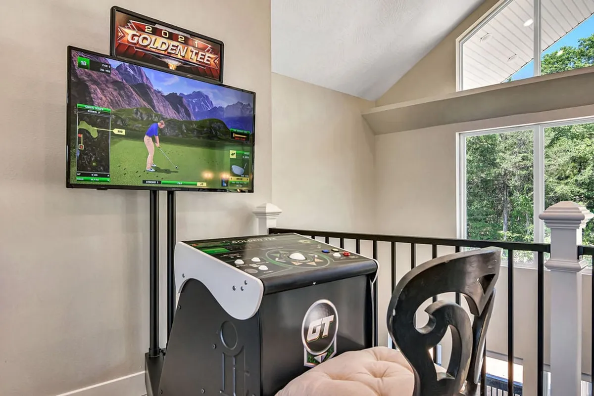 A vibrant interior space with an arcade golf machine, a large screen TV, and a comfortable chair. The area exudes fun and relaxation, making it ideal for friendly competitions, brainstorming sessions, or unwinding after a day’s activities. The upscale furnishings and playful features appeal to both corporate and leisure gatherings.