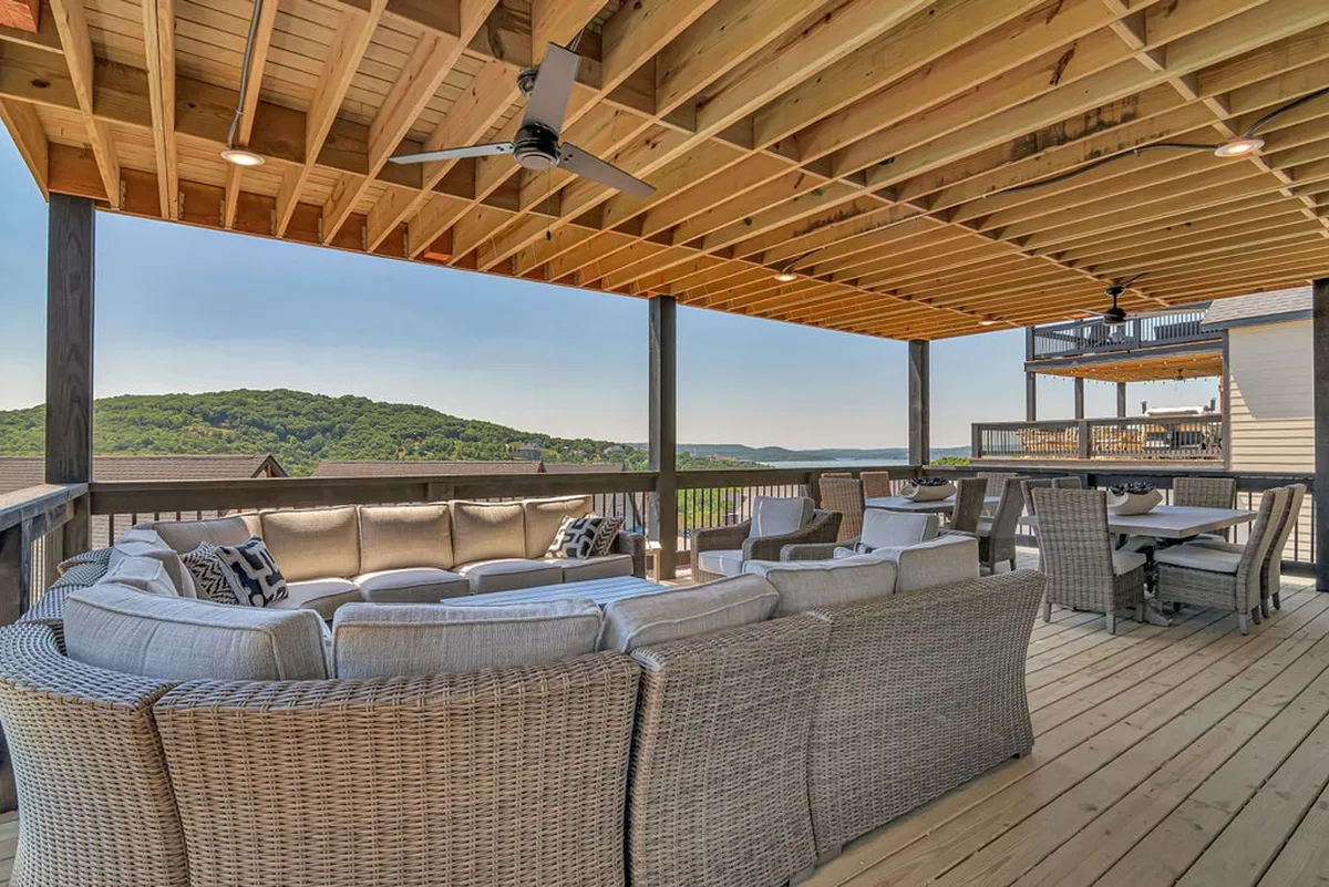 A spacious outdoor deck outfitted with a large sectional sofa, a dining area, and sweeping views of rolling hills. The setting is perfect for both social gatherings and tranquil moments, emphasizing comfort and luxurious outdoor living. The arrangement invites group conversations and celebrations in a sophisticated but relaxed environment.
