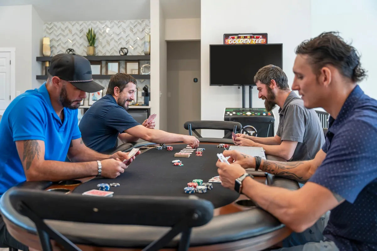 A poker table is the focal point, surrounded by players with poker chips and cards in hand, suggesting social and competitive gameplay in a welcoming environment.