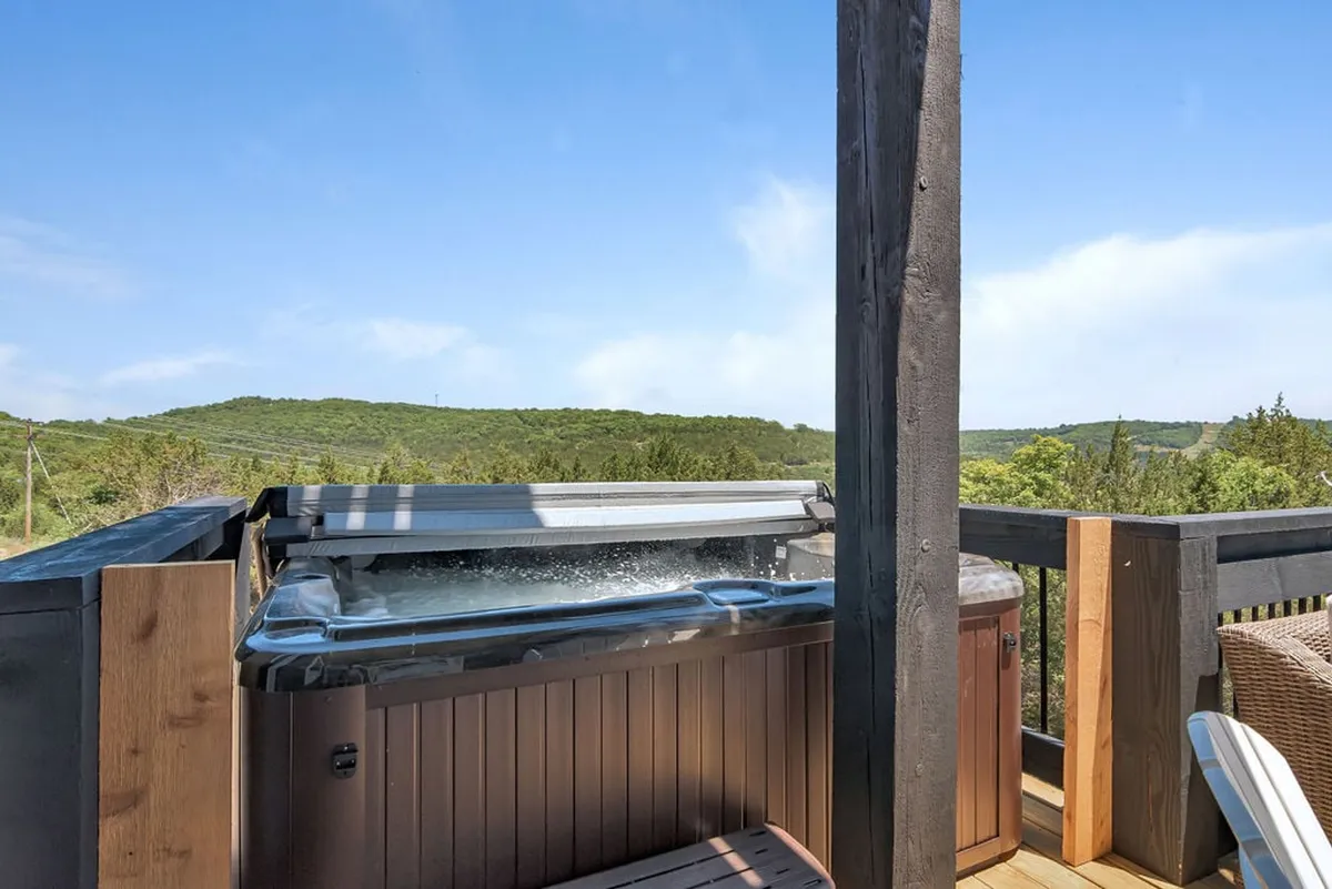 A scenic exterior area featuring a hot tub enclosed by a wooden railing, with expansive views of the natural landscape beyond. The space feels relaxed and private, making it an ideal retreat for both owners and their pets to enjoy the outdoors together.